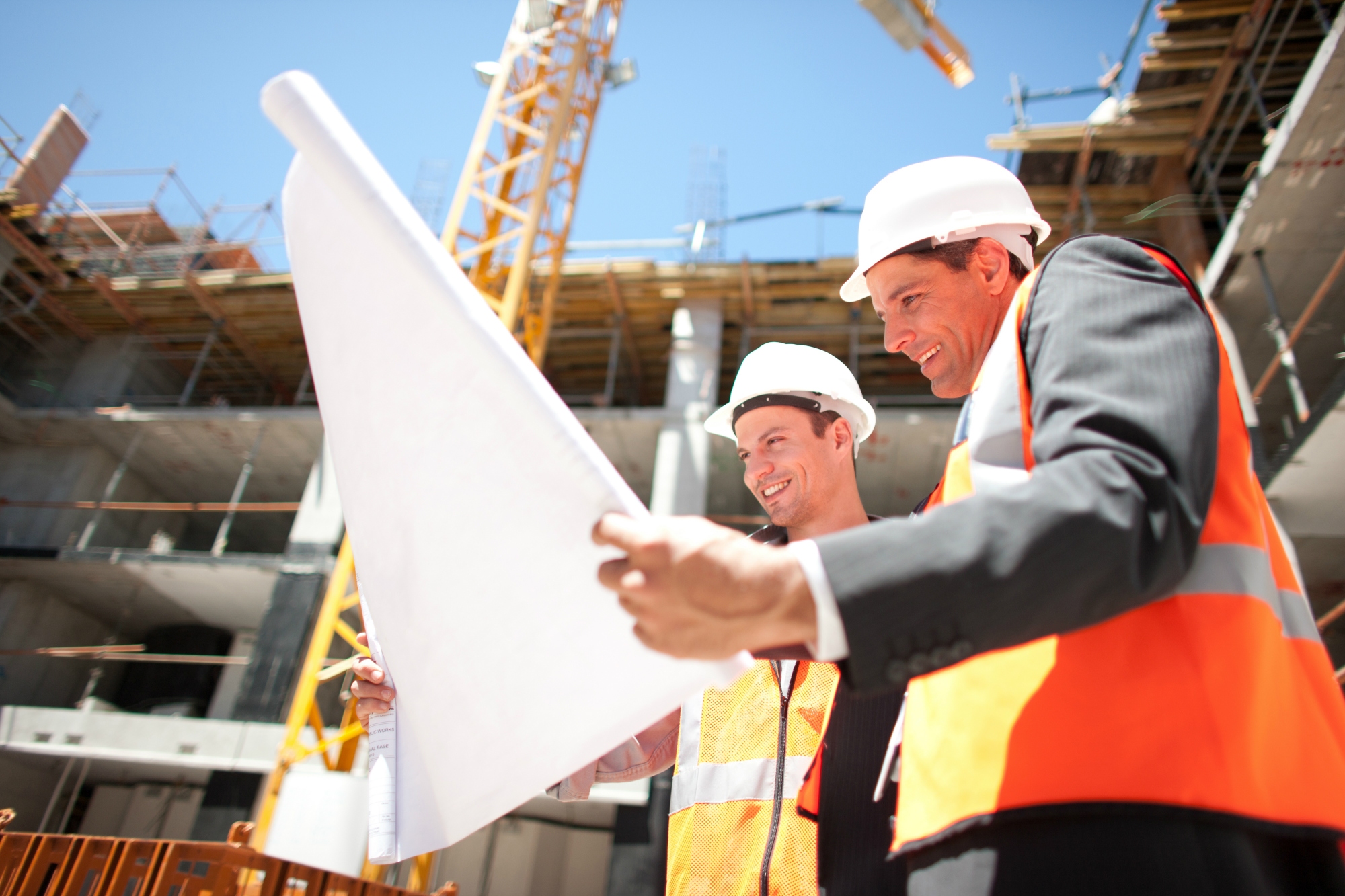 Two Construction Workers Holding Blueprint at Construction Site