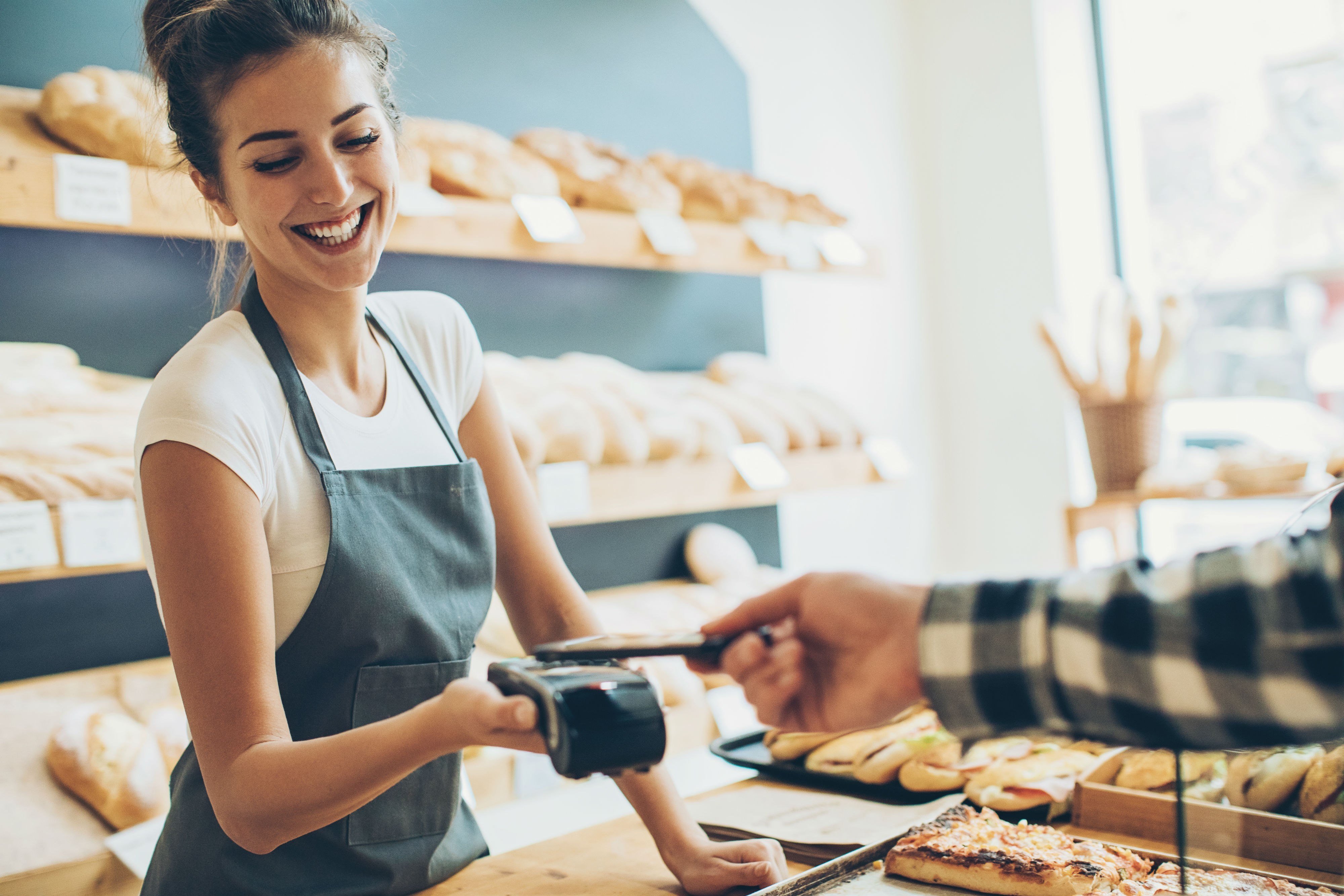 Woman Behind Bakery Counter Cashing Out Customer