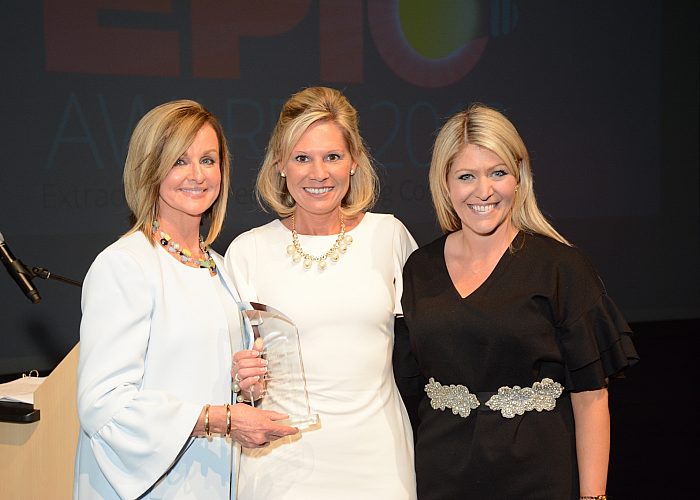 Three Women Smile While Holding an Award