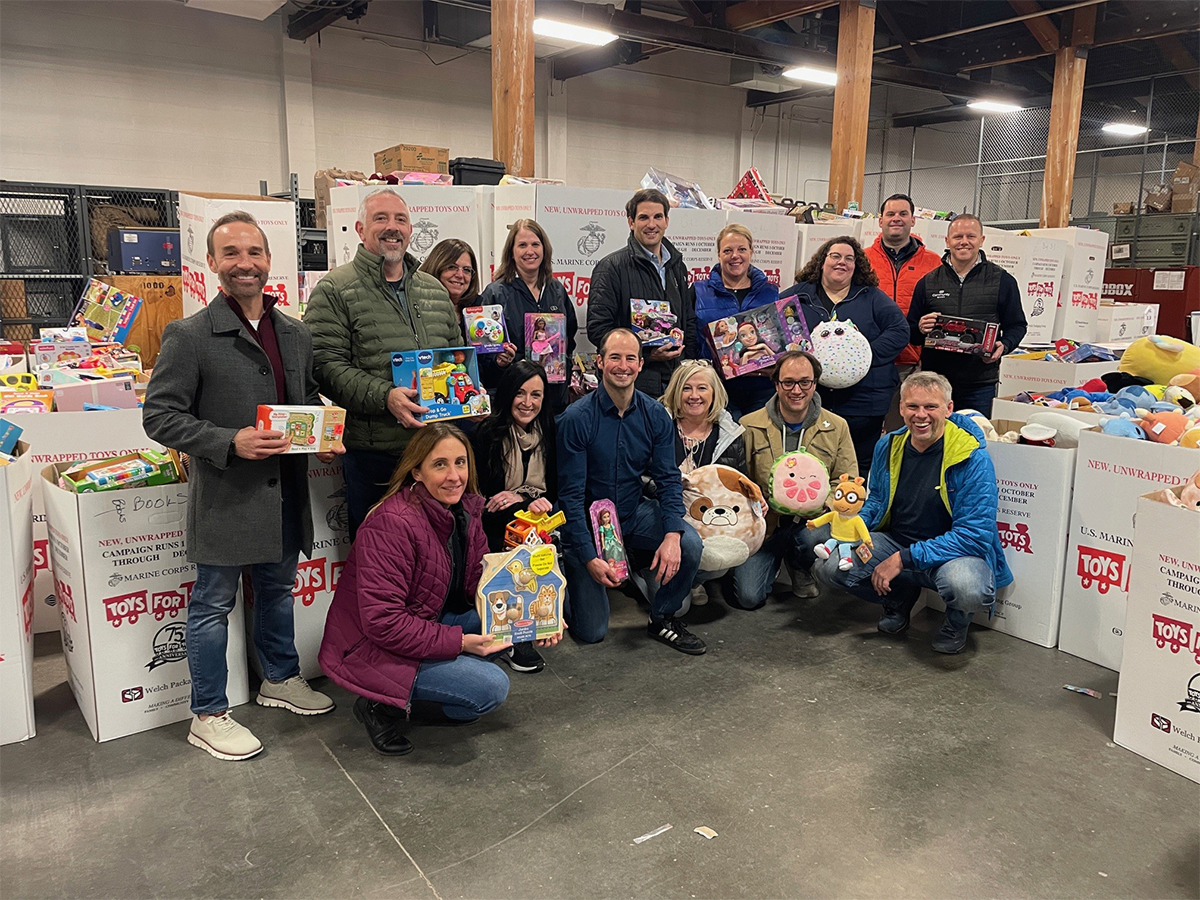 CBNA team holding toys at "Toys-For-Tots" warehouse