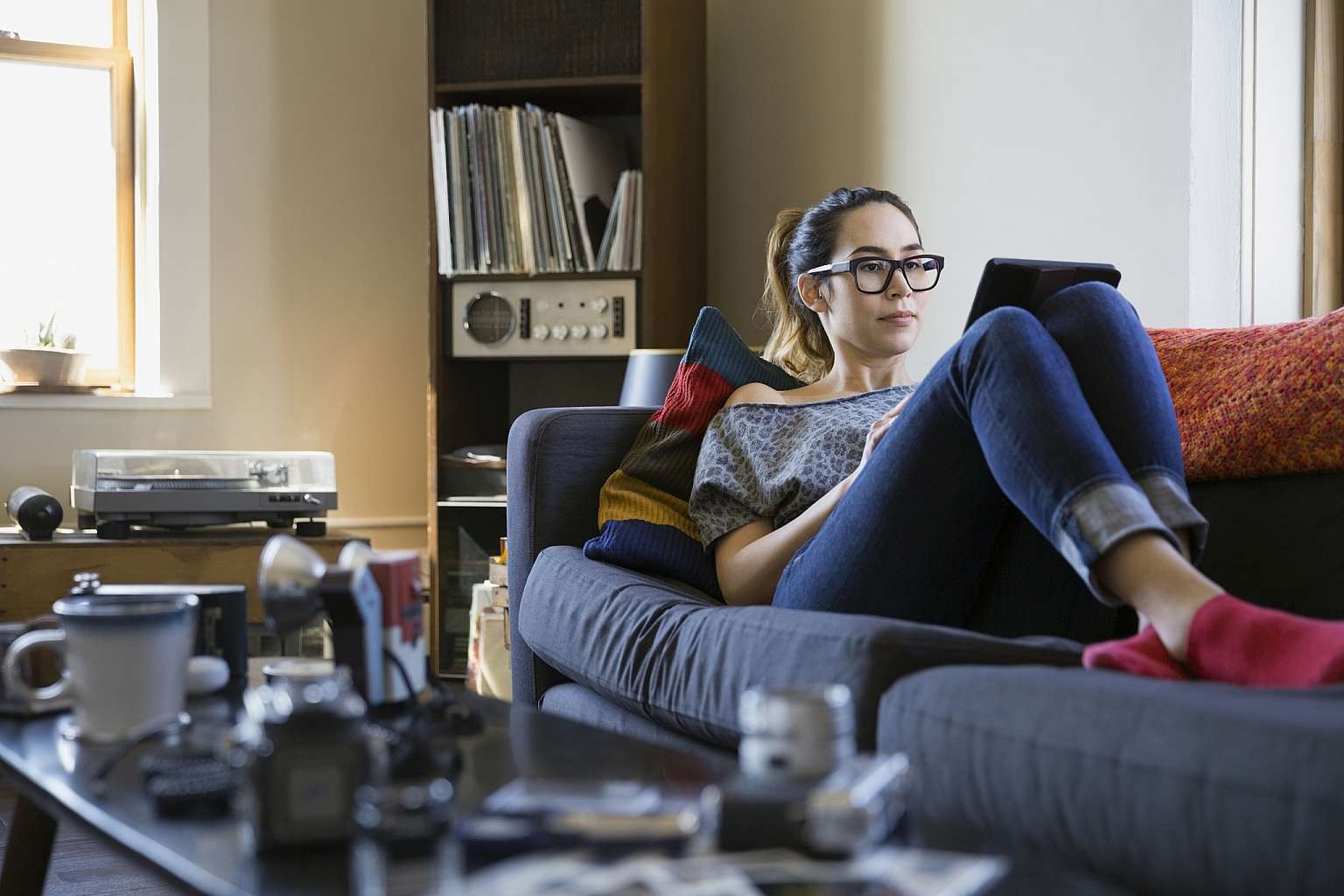 Woman Using Digital Tablet While Laying on Couch