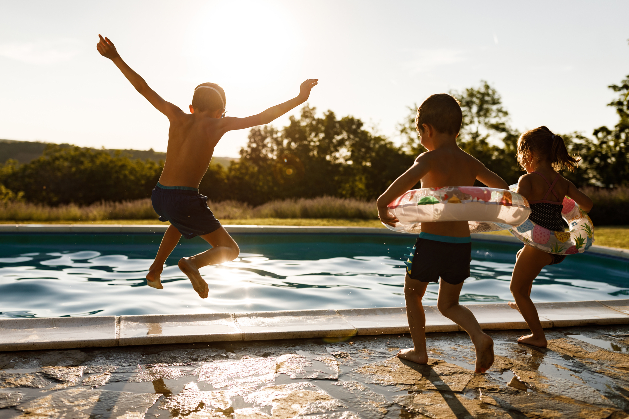 Three-kids-jumping-into-pool