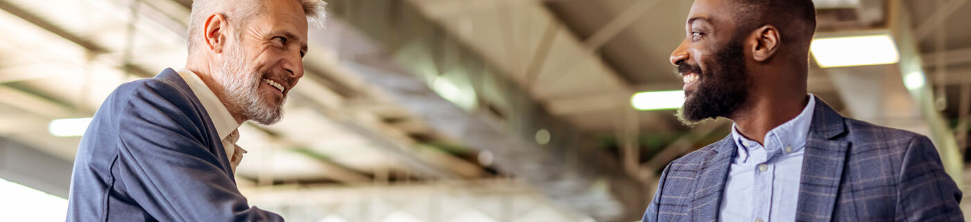 Header cre two men warehouse shaking hands axiom