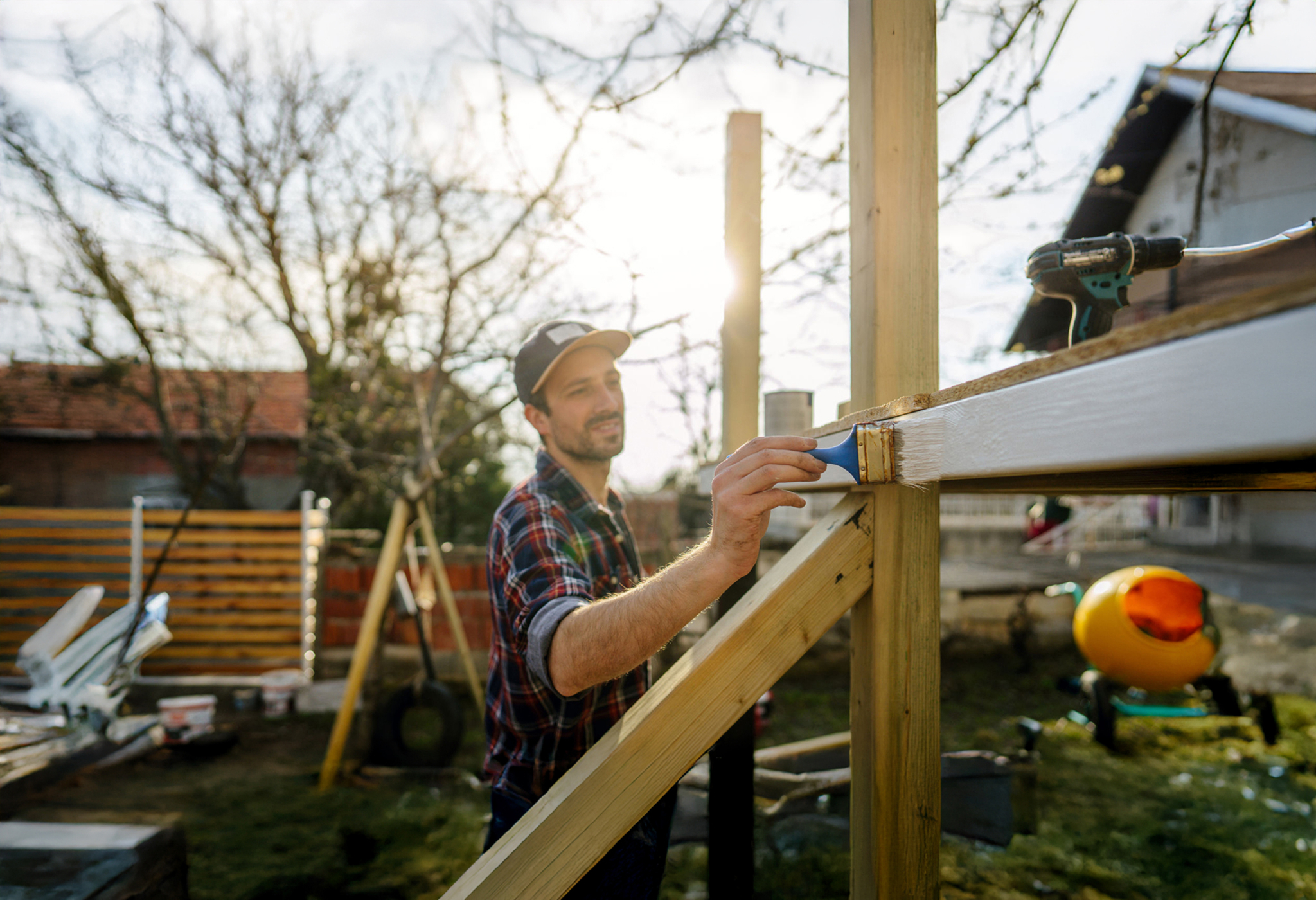 A man staining wood in a back yard setting