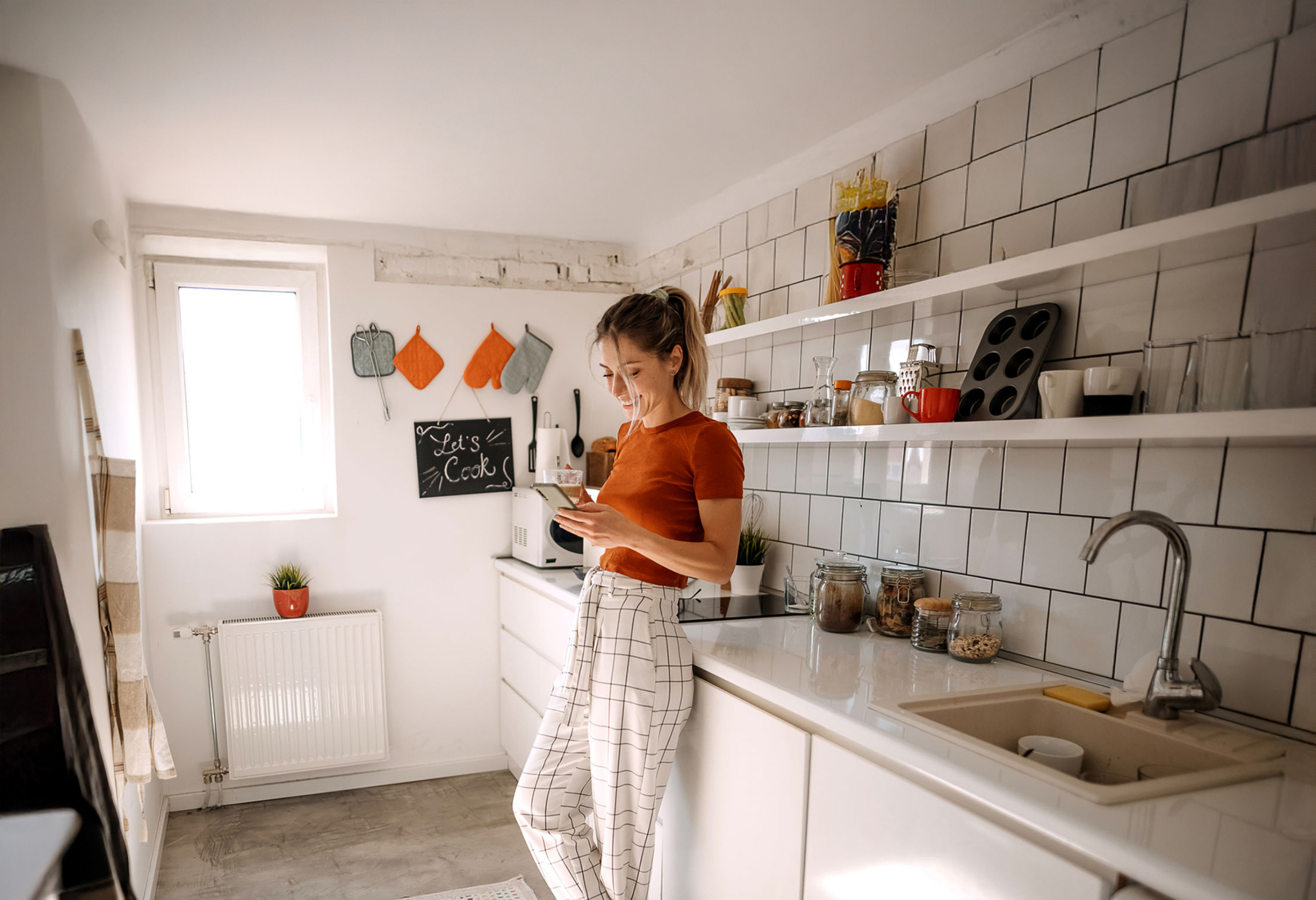 A woman looking at her mobile phone in a kitchen setting